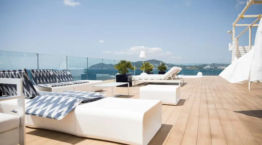 a roof top deck area with white bright lounge chairs and spa overlooking the blue ocean on a sunny t20 ro7Ydd