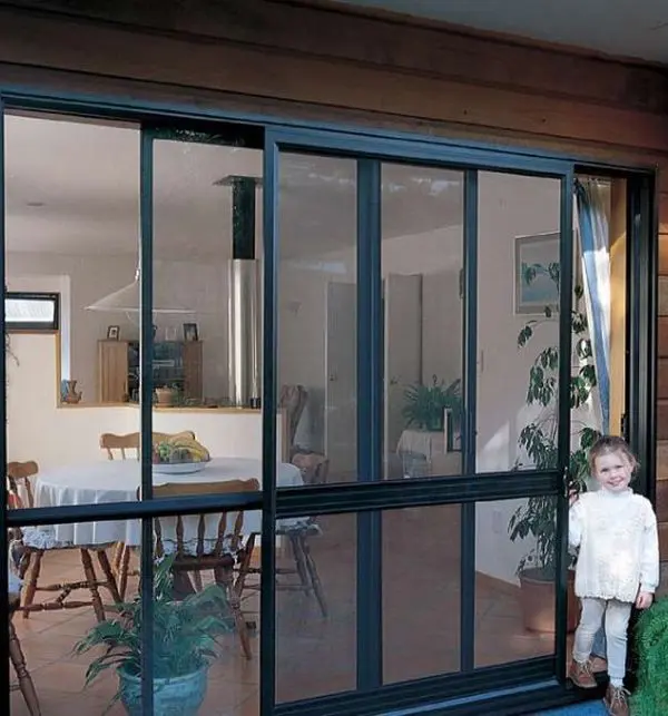Dark framed sliding screen doors opening from a family dining room to the garden